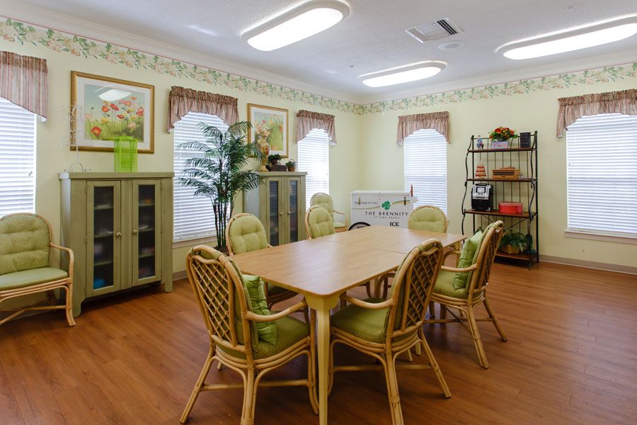 A cozy meeting room with wicker chairs and a wooden table, adorned with plants and decorated with art on the walls.