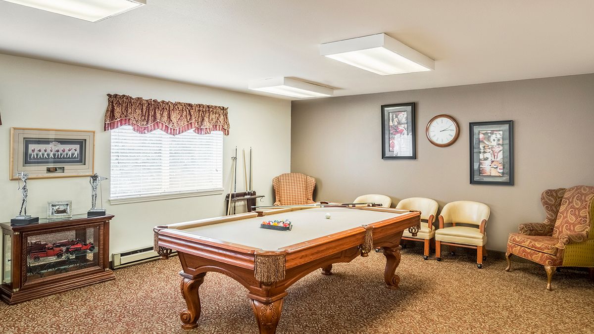 A cozy billiards room featuring a classic pool table surrounded by comfortable seating.
