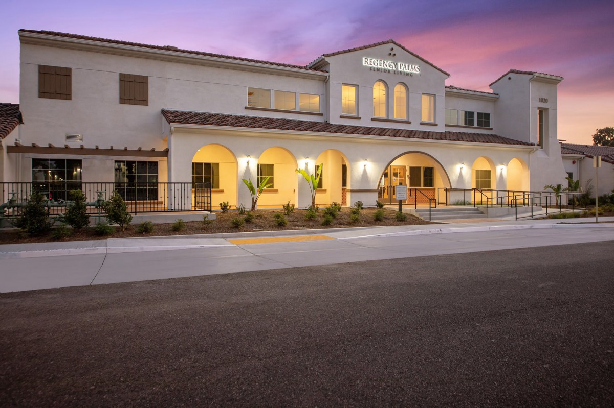 A well-lit Mediterranean-style building at dusk with an inviting entrance.