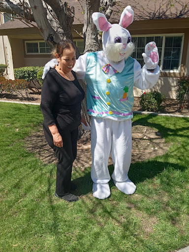 A person posing with the Easter Bunny costume in a sunny outdoor setting.