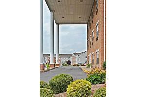 A building entrance with tall columns and neatly landscaped surroundings.