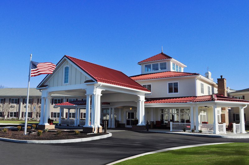 A modern building with a red roof and a prominent entrance featuring columns, under a clear blue sky.