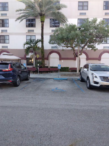 A view of a parking lot with two parked cars and a building in the background.