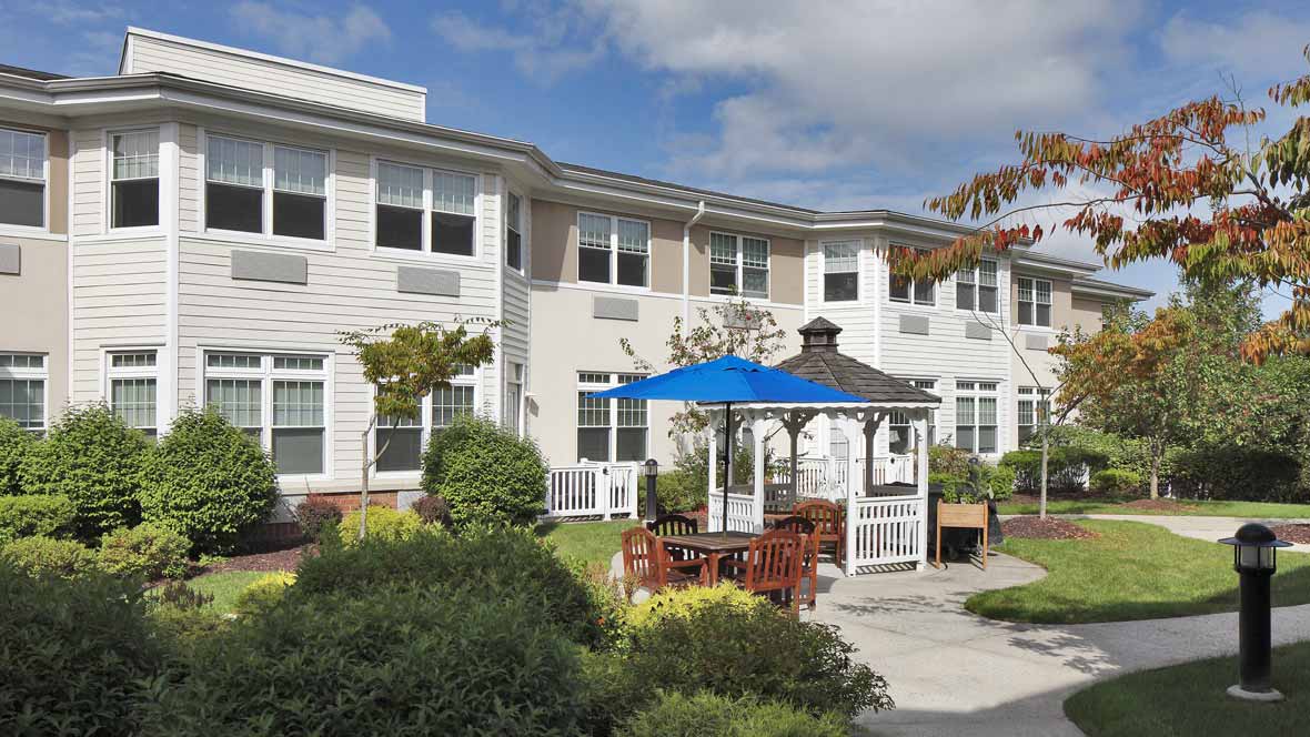 A residential building with a landscaped garden and a gazebo under a clear sky.