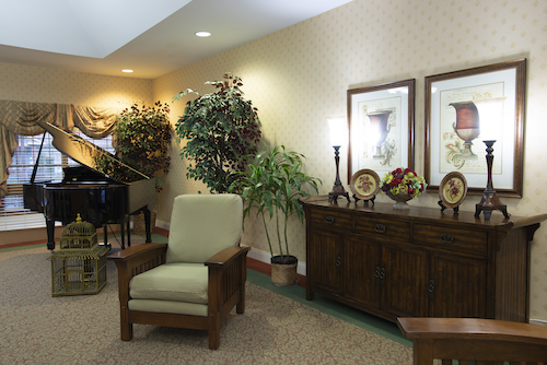 A cozy lobby area featuring comfortable seating, decorative plants, and a piano.