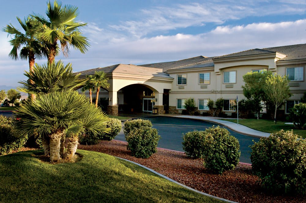 A hotel building with palm trees and landscaped surroundings.