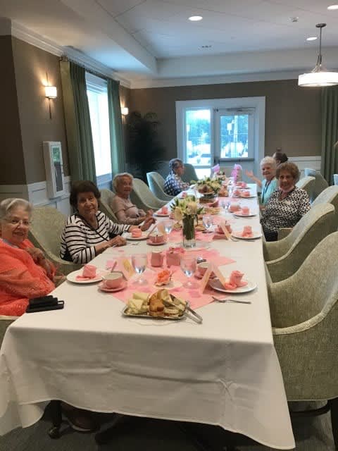 A group of elderly people enjoying a meal together at a beautifully set table indoors.