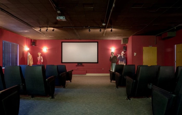 A cozy home theater with red walls, a large screen, and comfortable seating.