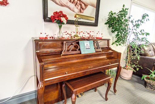 A beautifully polished wooden piano accompanied by decorative elements and a piece of art on the wall.