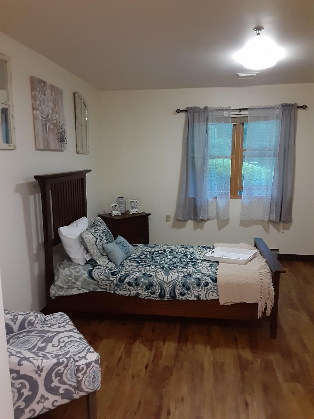 A cozy bedroom with a single bed, decorated with patterned bedding and complemented by soft curtains.