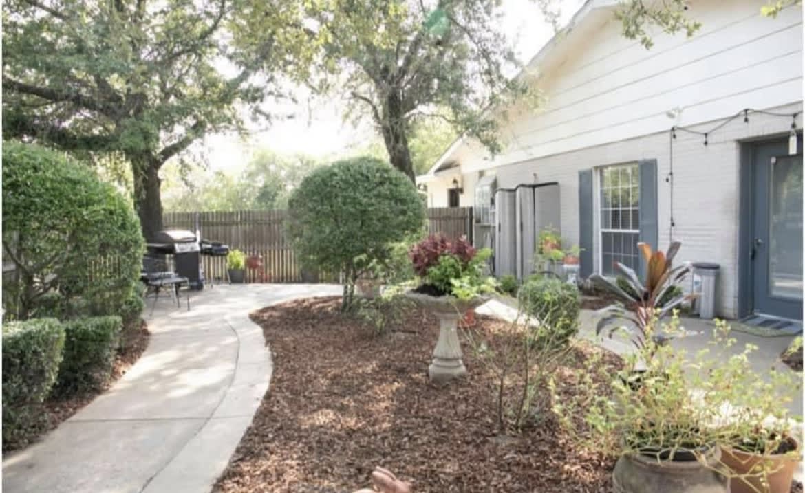 A serene garden with a winding pathway surrounded by trees and well-maintained plants.