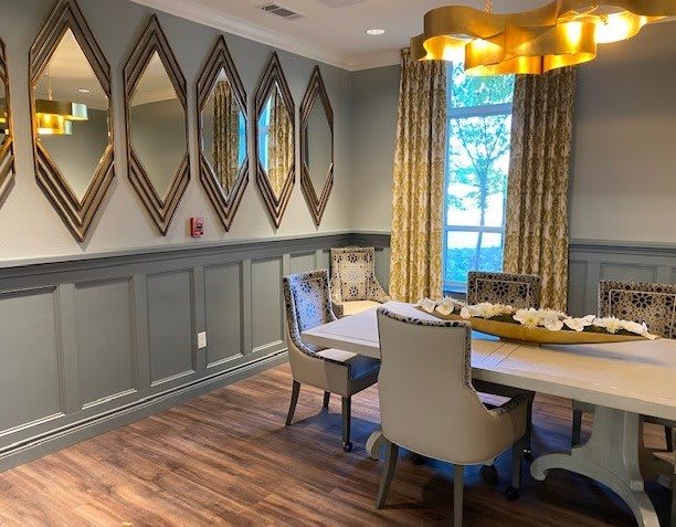 A modern dining room with a stylish chandelier, mirrored wall decor, and elegant furnishings.