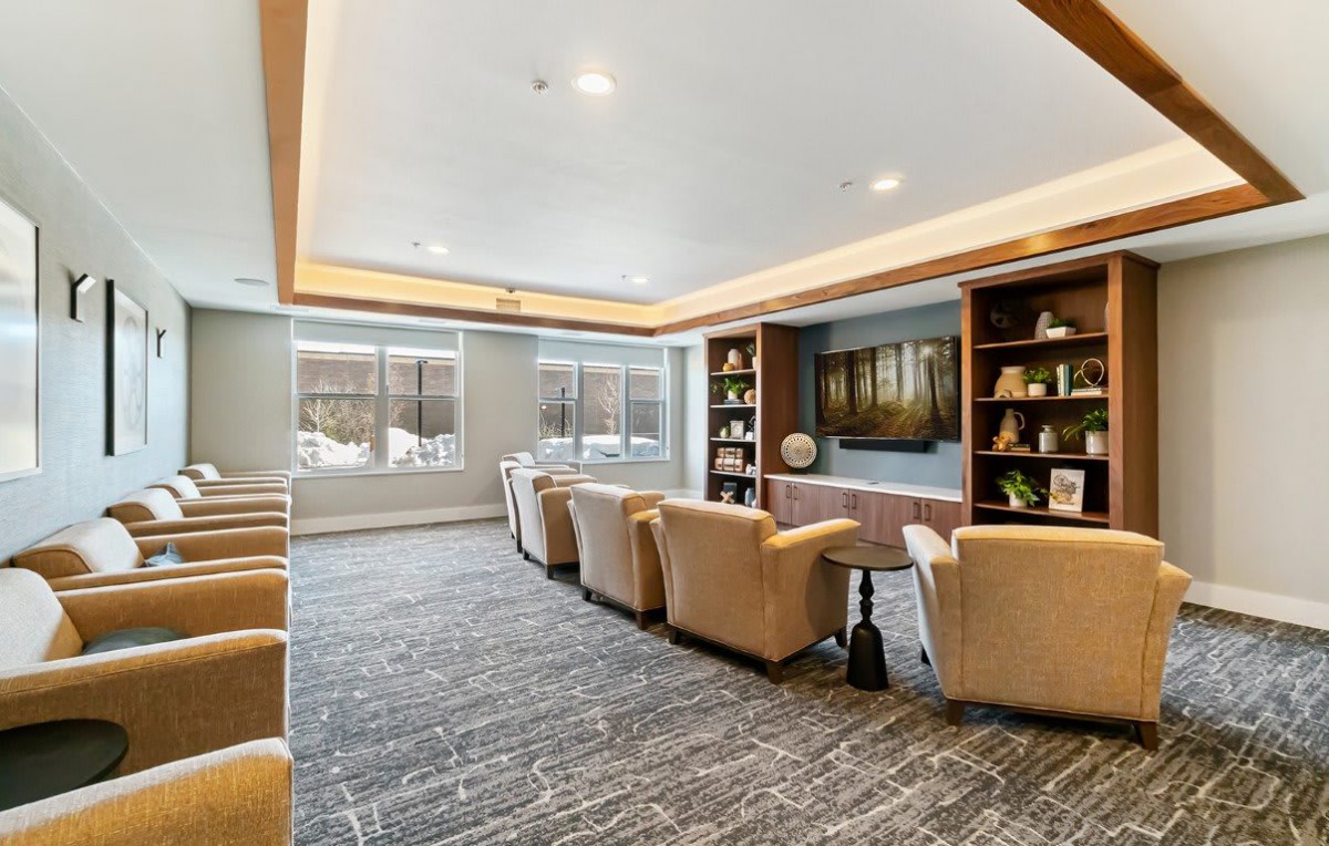 A modern lounge area with comfortable armchairs, bookshelves, and large windows.