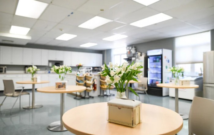 A modern kitchen interior with tables and chairs, decorated with flowers.