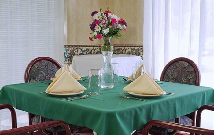 A beautifully set dining table with a floral centerpiece and neatly arranged napkins and glasses.