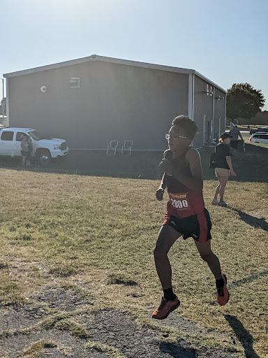 A young athlete sprinting during a running competition on a sunny day.
