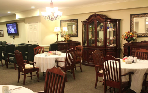 A cozy dining room featuring a wooden table set for a meal, elegant chairs, and a vintage cabinet.