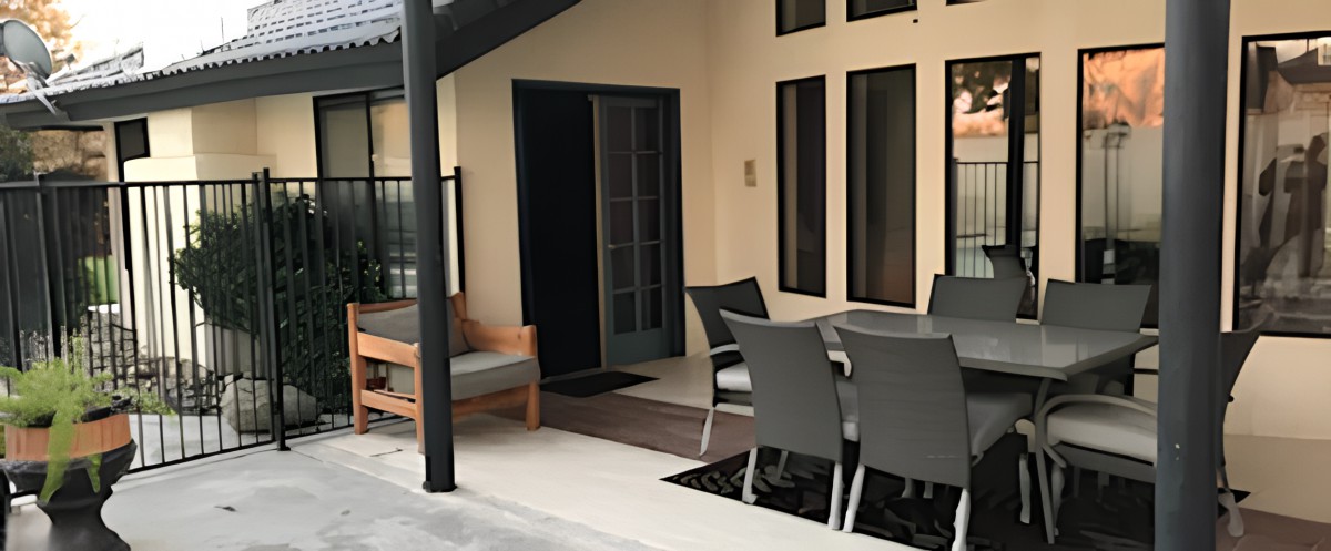 A cozy patio area with modern outdoor furniture and a table, perfect for relaxation.