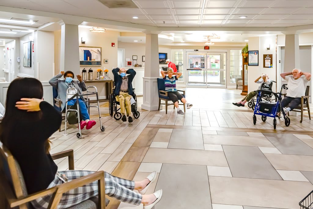 A group of elderly individuals participating in an exercise session inside a nursing home.