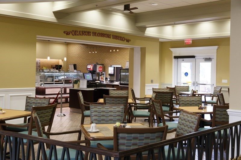 An empty restaurant interior with tables and chairs arranged for dining, featuring a cafe counter in the background.