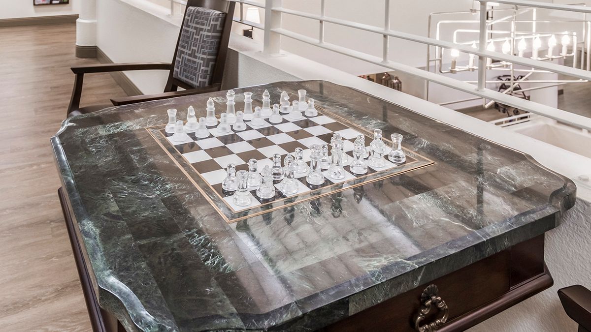 A stylish glass chess set on a decorative table in an indoor setting.
