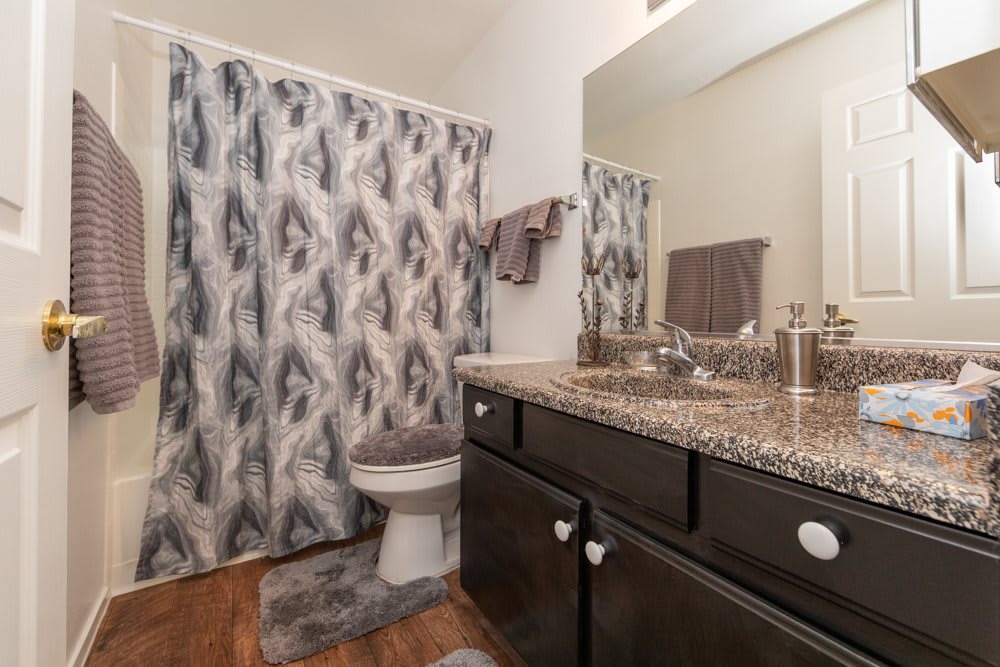 A modern bathroom with a granite countertop and patterned shower curtain.