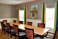 A well-lit conference room featuring a long table, chairs, and decorative artwork on the wall.