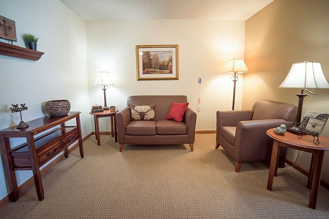 A cozy living room with a sofa, armchair, and warm lighting.