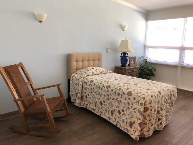 A cozy bedroom with a bed, rocking chair, and nightstand.