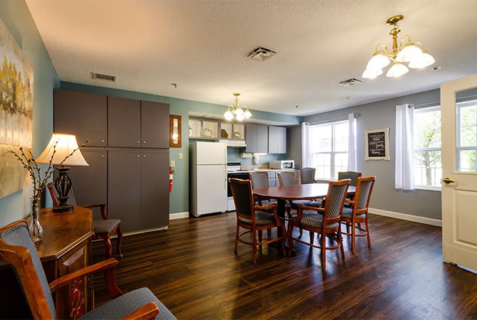 A cozy kitchen and dining area with wooden flooring, complete with a table, chairs, and various appliances.