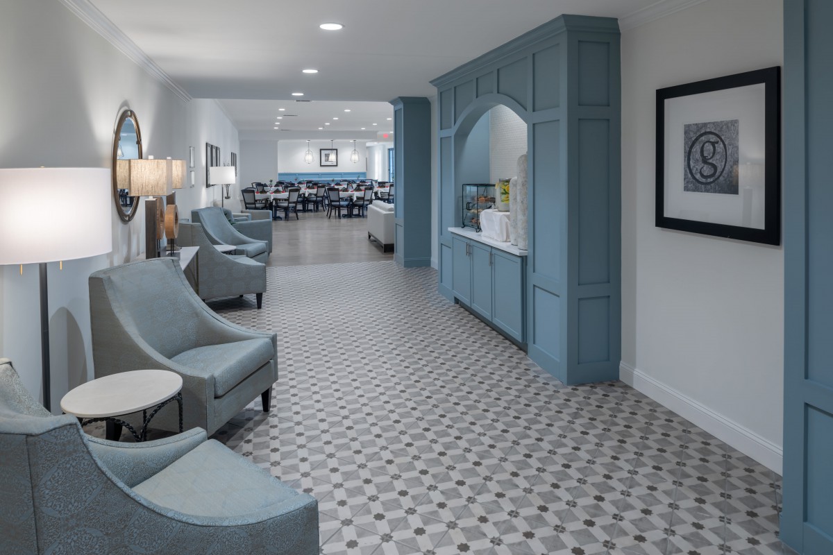A modern lounge area with blue seating and cabinetry, featuring a tiled floor and contemporary design.