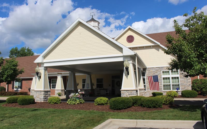 A residential building with a porch and well-maintained lawn.