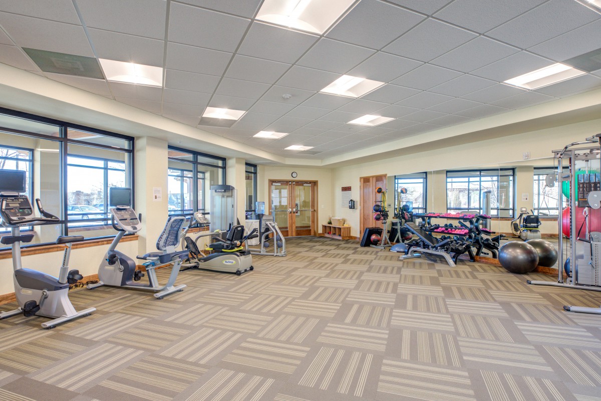 A spacious and well-lit gym with various exercise equipment.