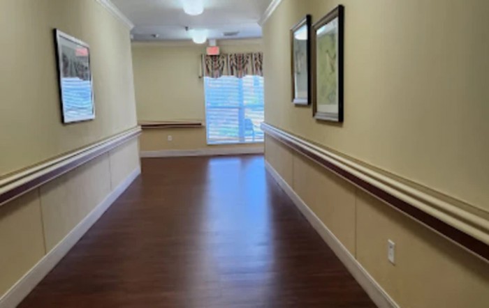 A clean, well-lit hallway with wooden flooring and framed pictures on the wall.