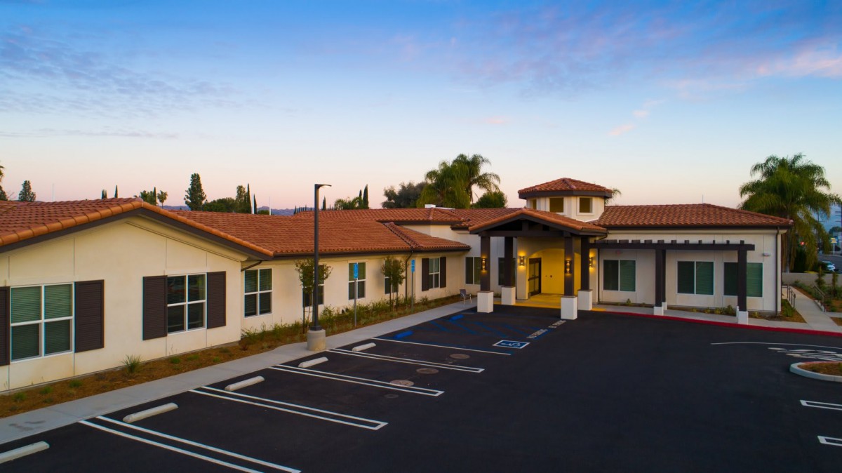 A modern building with a parking lot at sunset.