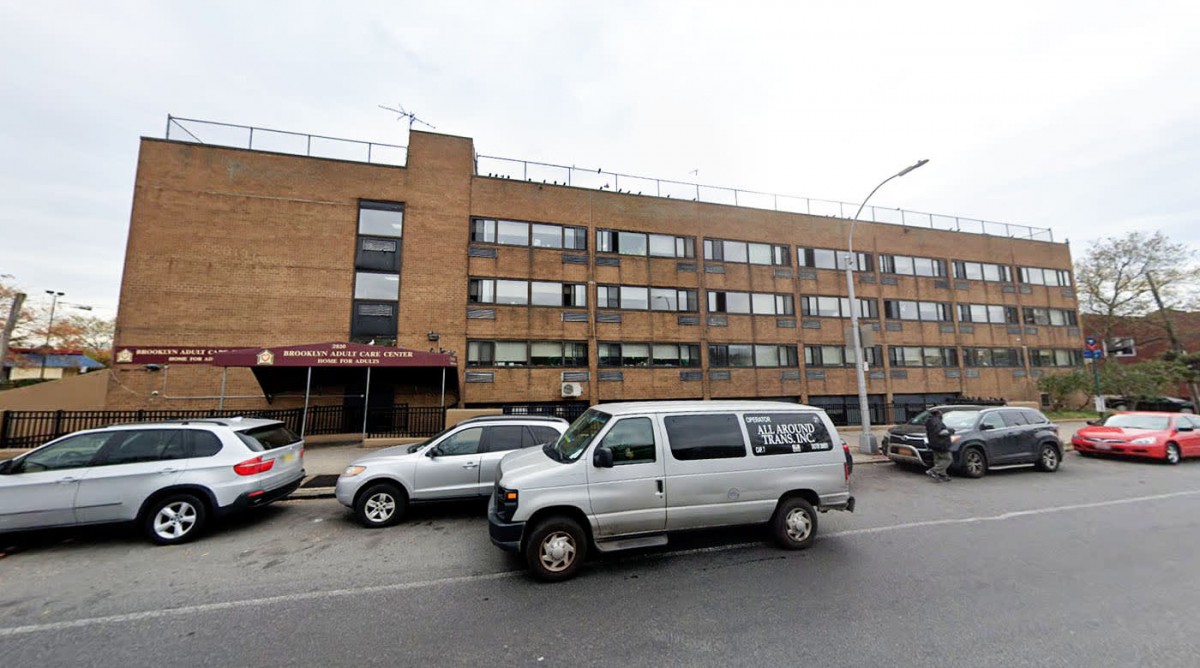 A city street featuring a multistory brick building with parked vehicles.