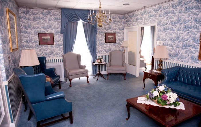 A traditional living room with floral wallpaper, elegant drapes, and comfortable armchairs.