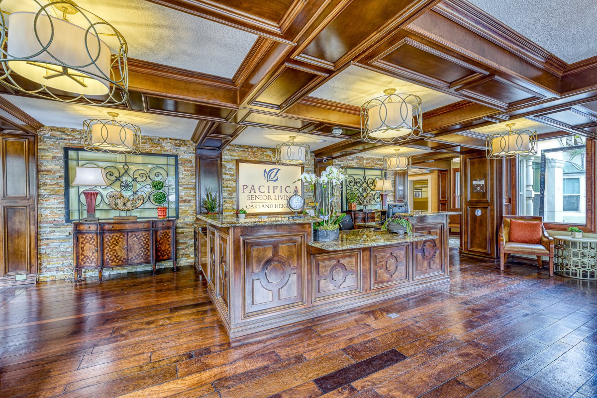 A luxurious hotel lobby with a wooden reception desk and elegant coffered ceiling.