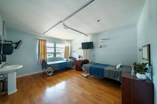 A spacious and well-lit hospital patient room featuring two beds and modern amenities.