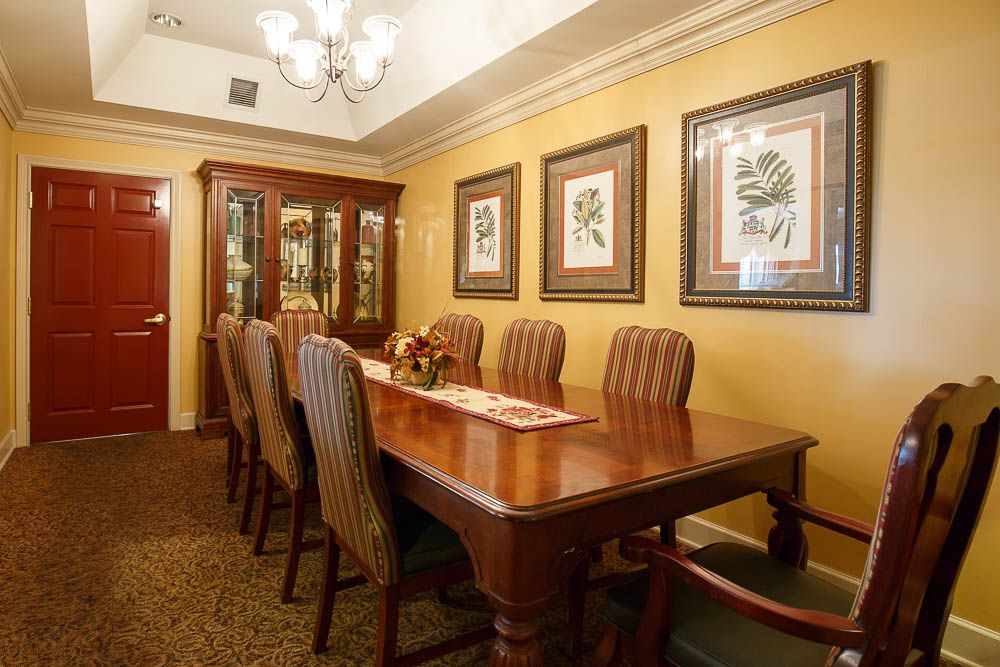 A classic dining room with an elegant wooden table, upholstered chairs, and framed artwork on the walls.