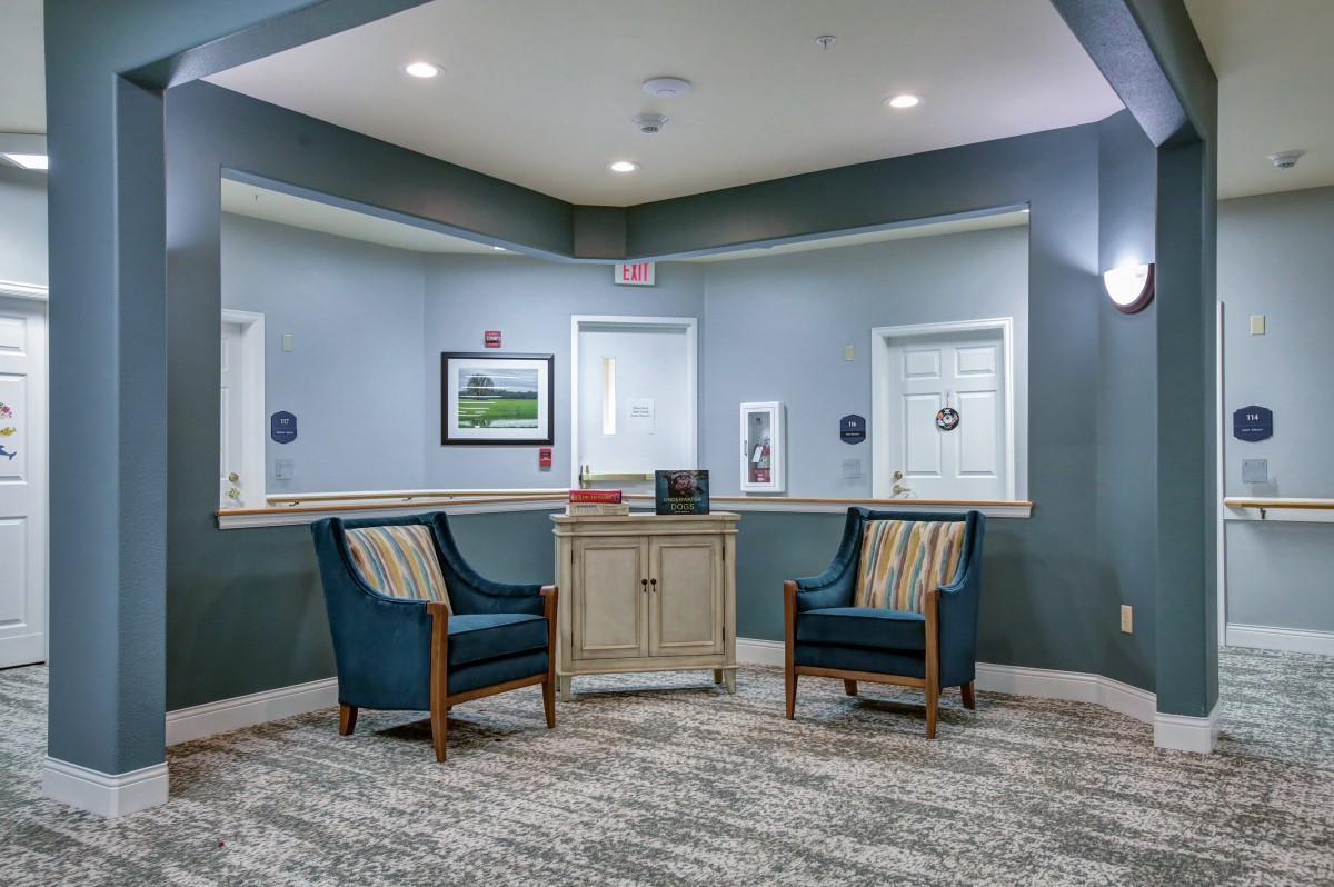 A cozy waiting area with two chairs and a small cabinet.