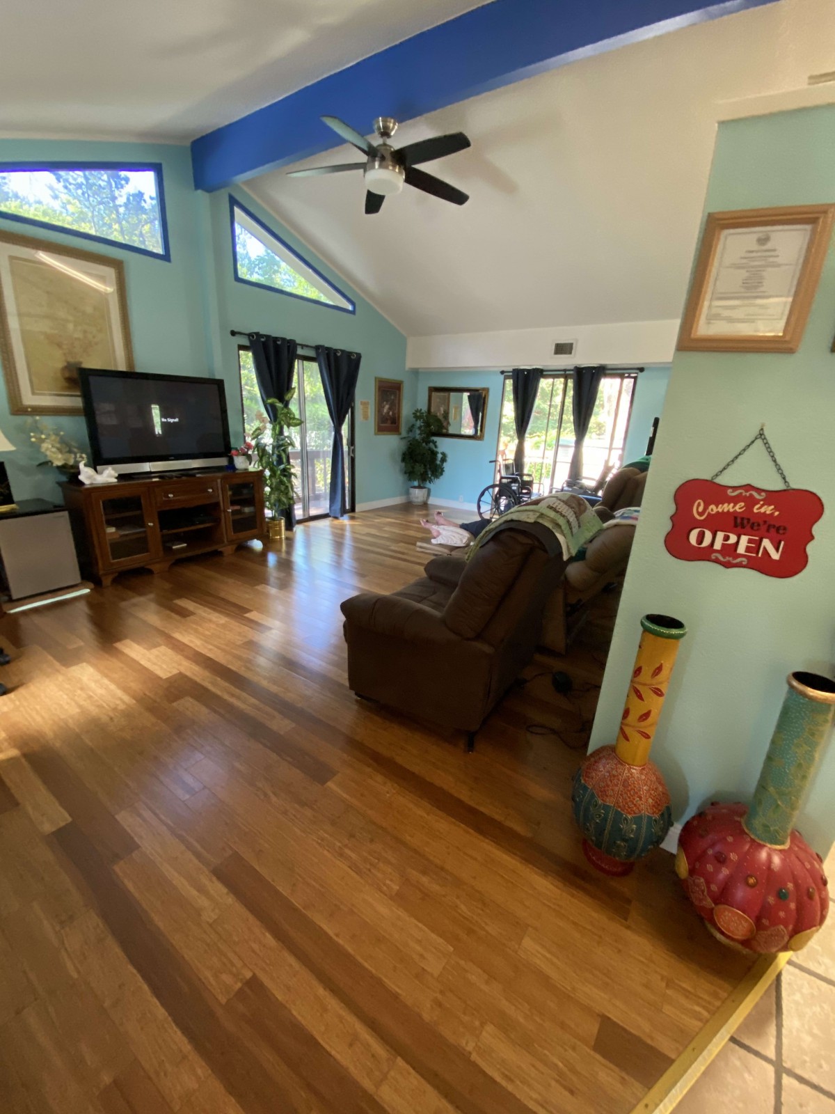 A cozy living room with hardwood flooring, comfortable seating, and a large television.