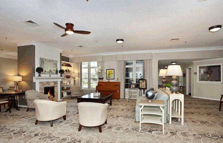 A cozy and elegantly designed living room with a fireplace, bookshelves, and comfortable seating.