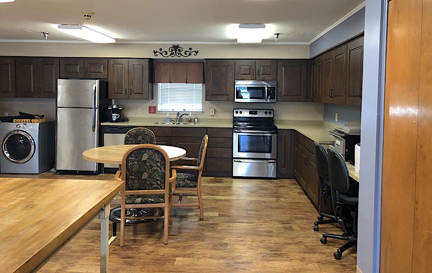 A modern kitchen with wooden cabinets, stainless steel appliances, and a dining area.