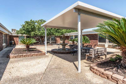 A serene outdoor patio area featuring shaded seating surrounded by greenery.