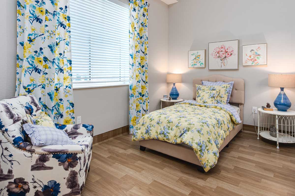 A cozy bedroom with floral patterns and soft lighting.