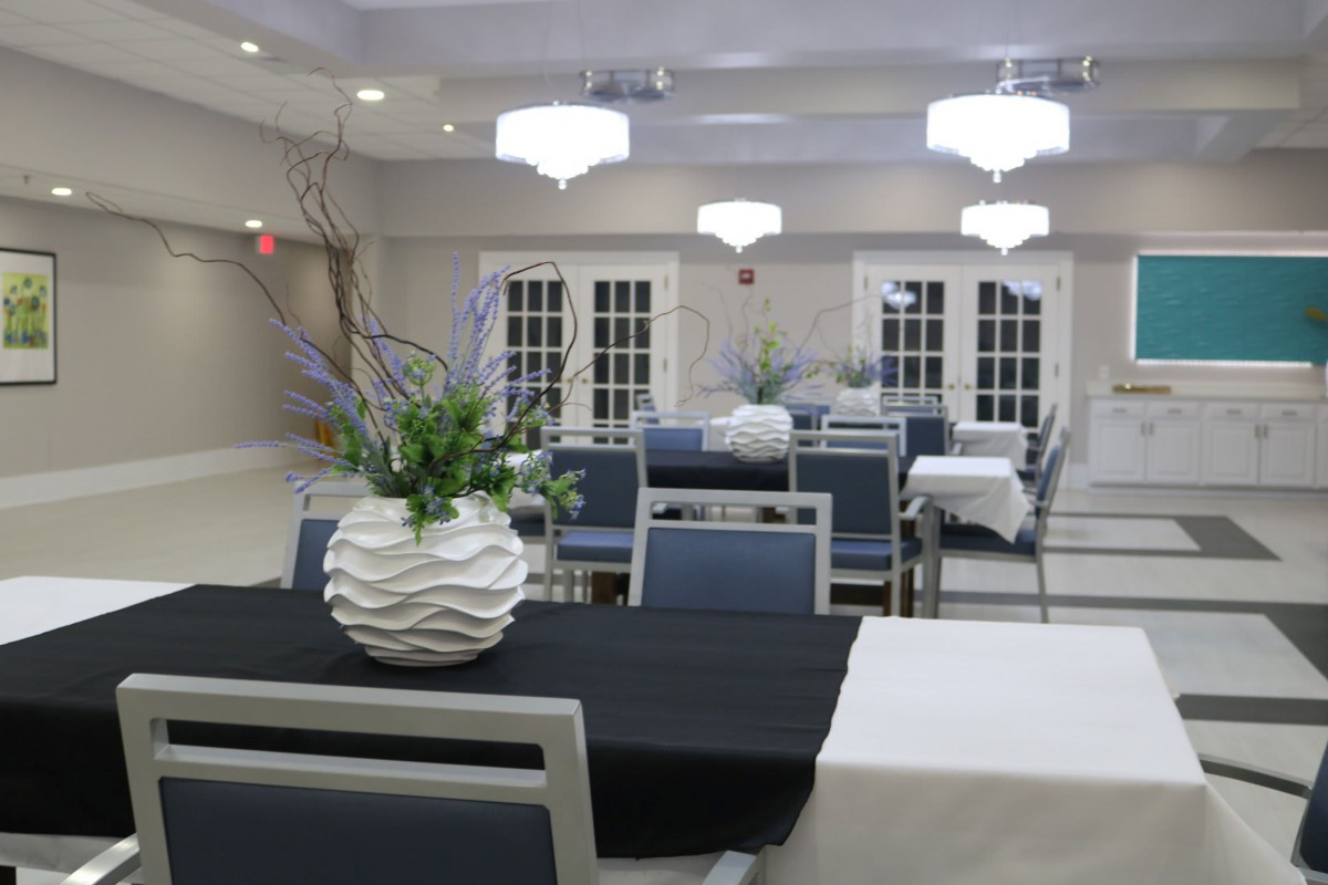 A well-decorated event hall with tables set and floral arrangements.