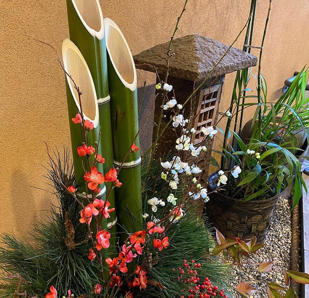 A traditional Japanese Kadomatsu arrangement featuring bamboo, pine branches, and colorful flowers.
