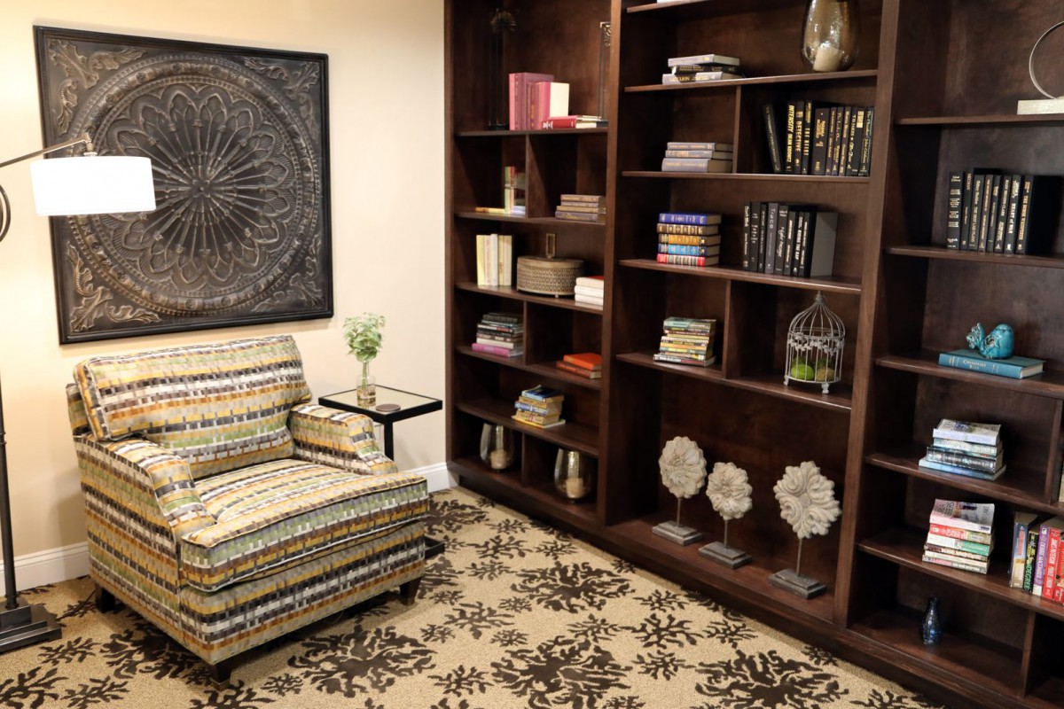 Cozy living room with a patterned armchair and a well-stocked bookshelf.