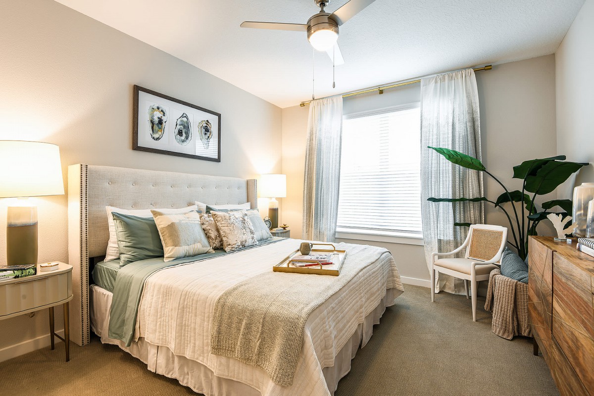A cozy and elegant bedroom with modern decor, featuring a neatly made bed, soft lighting, and a stylish ceiling fan.